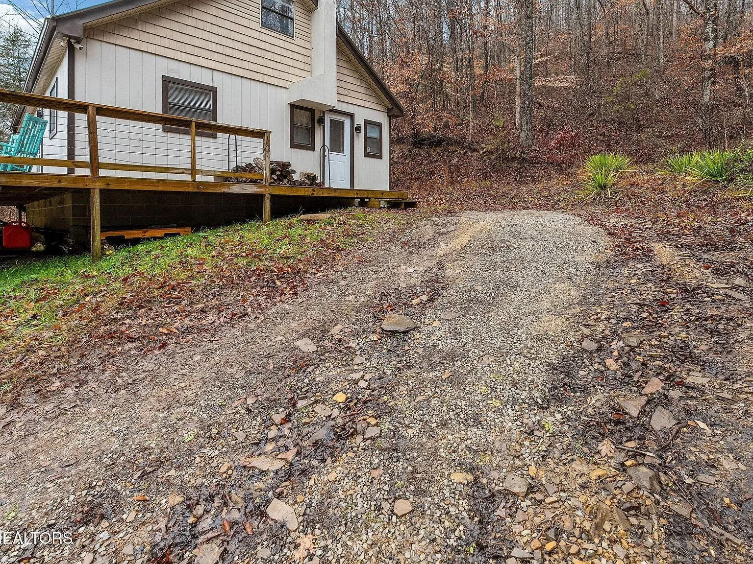 A gravel driveway leading toward an open field and distant barn