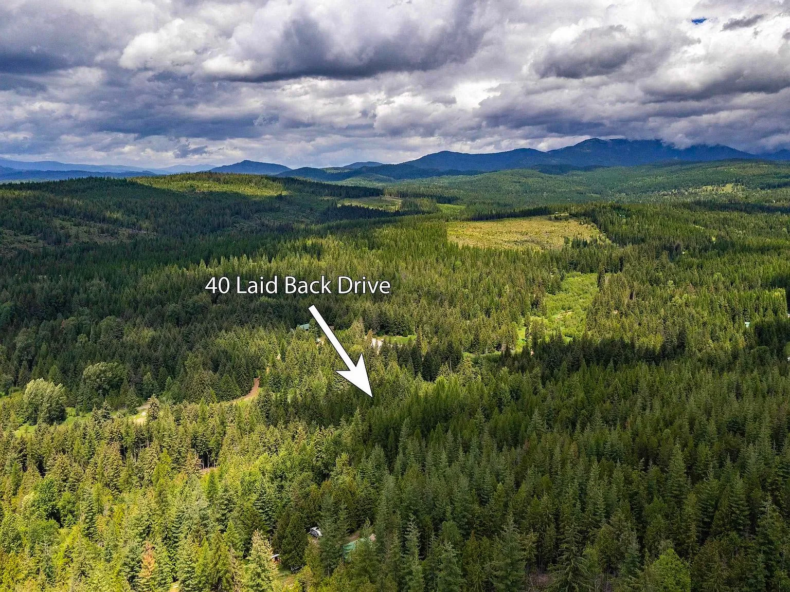 A wide aerial view of forested ridgelines and distant valley near the property