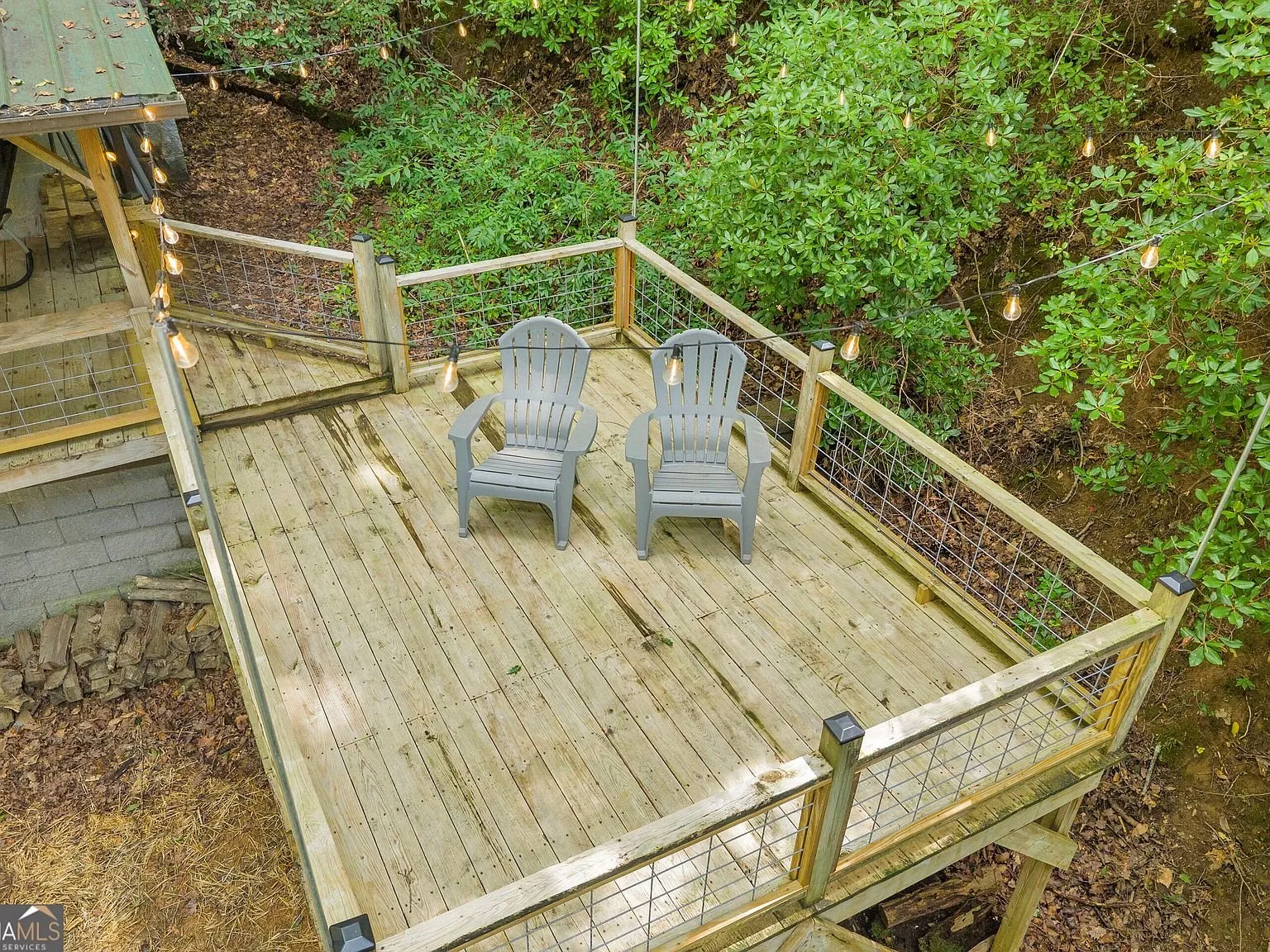 An elevated deck with two chairs overlooking the trees and creek below