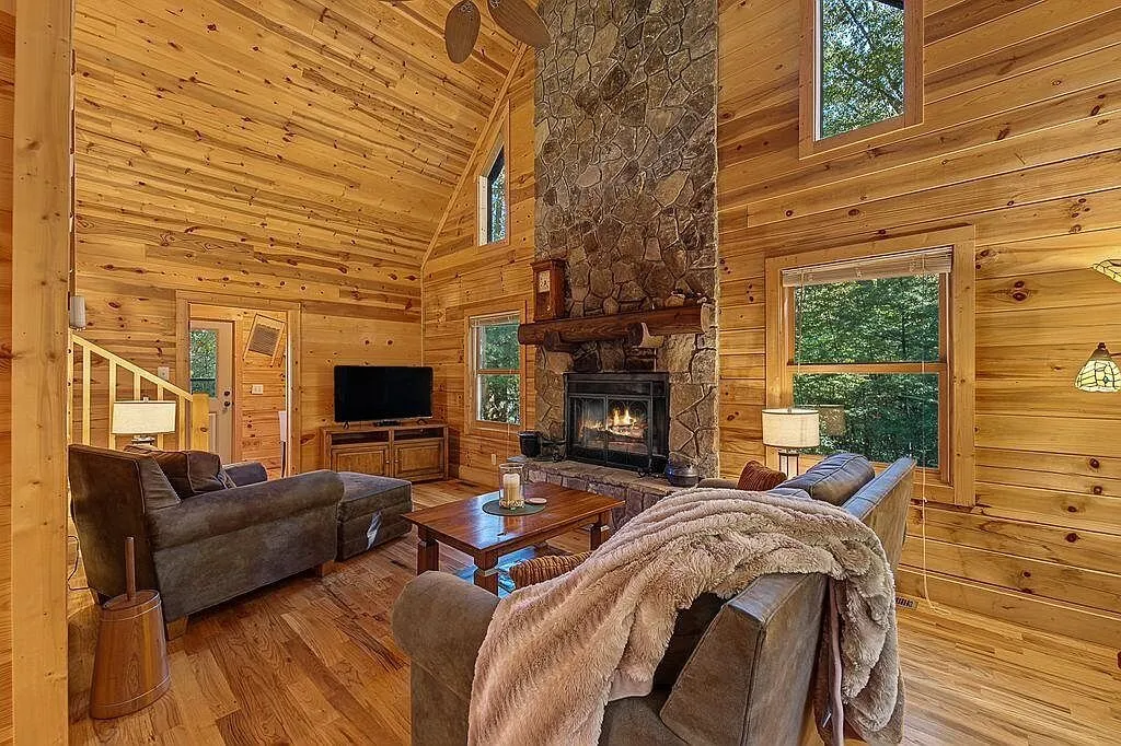 The great room's stone fireplace with a leather chair and blanket