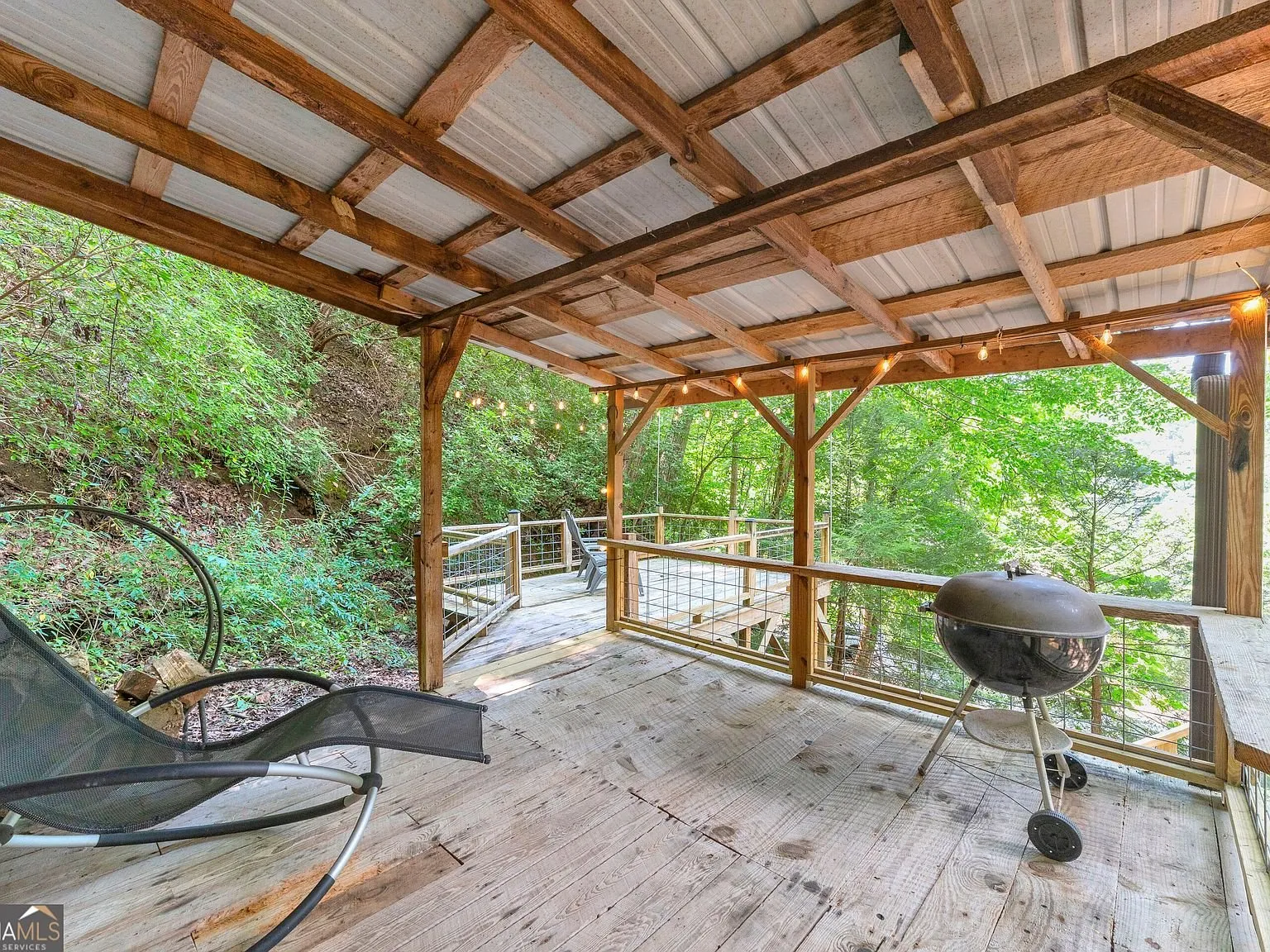 A covered deck area with outdoor furniture and a grill