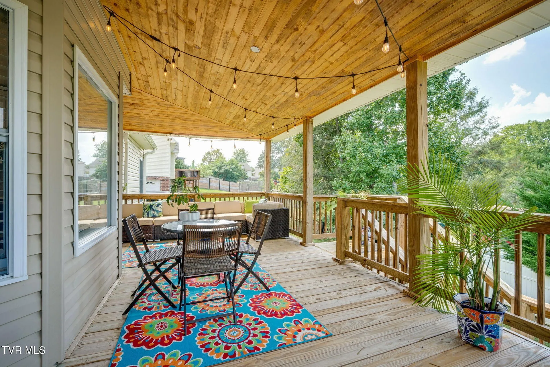 The covered back deck with its wood ceiling, string lights and bistro table