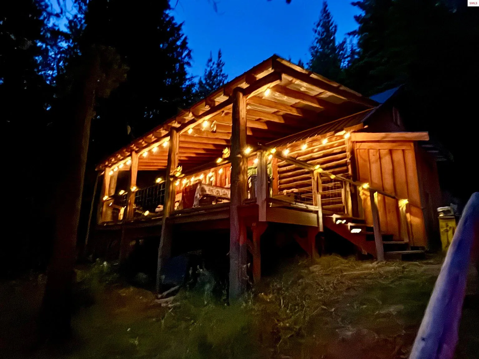 A wooded clearing on the property dotted with stacked firewood and stone