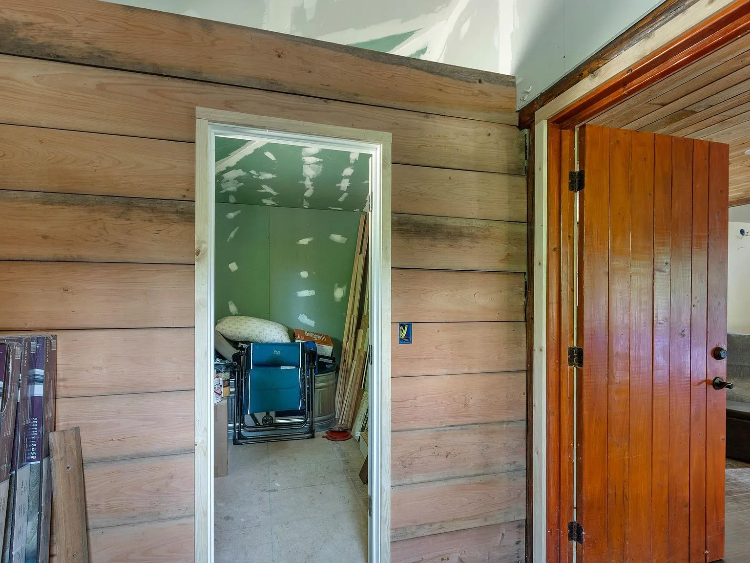 An unfinished room plumbed for a future bathroom, with green primed drywall and a wood door