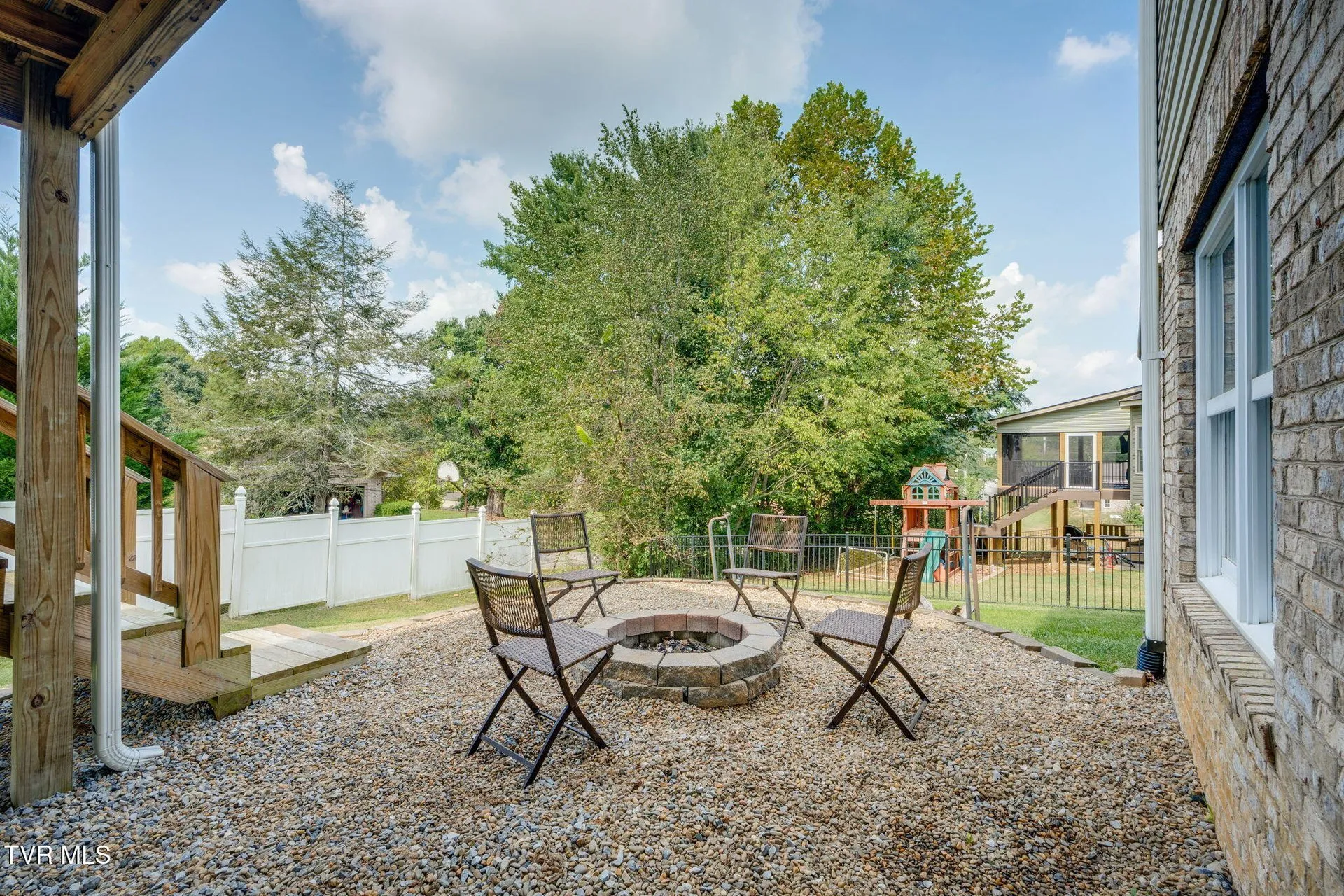 The fire pit area on gravel below the deck with chairs around it