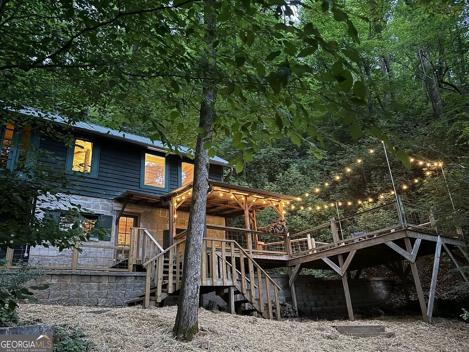 The cabin's exterior at dusk with string lights lit across the deck