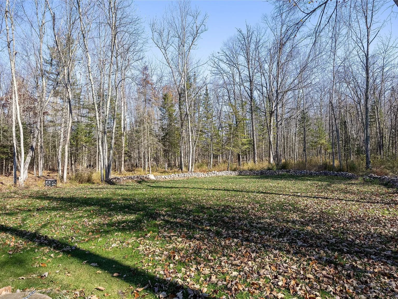 A second view of the cleared yard bordered by stacked stone