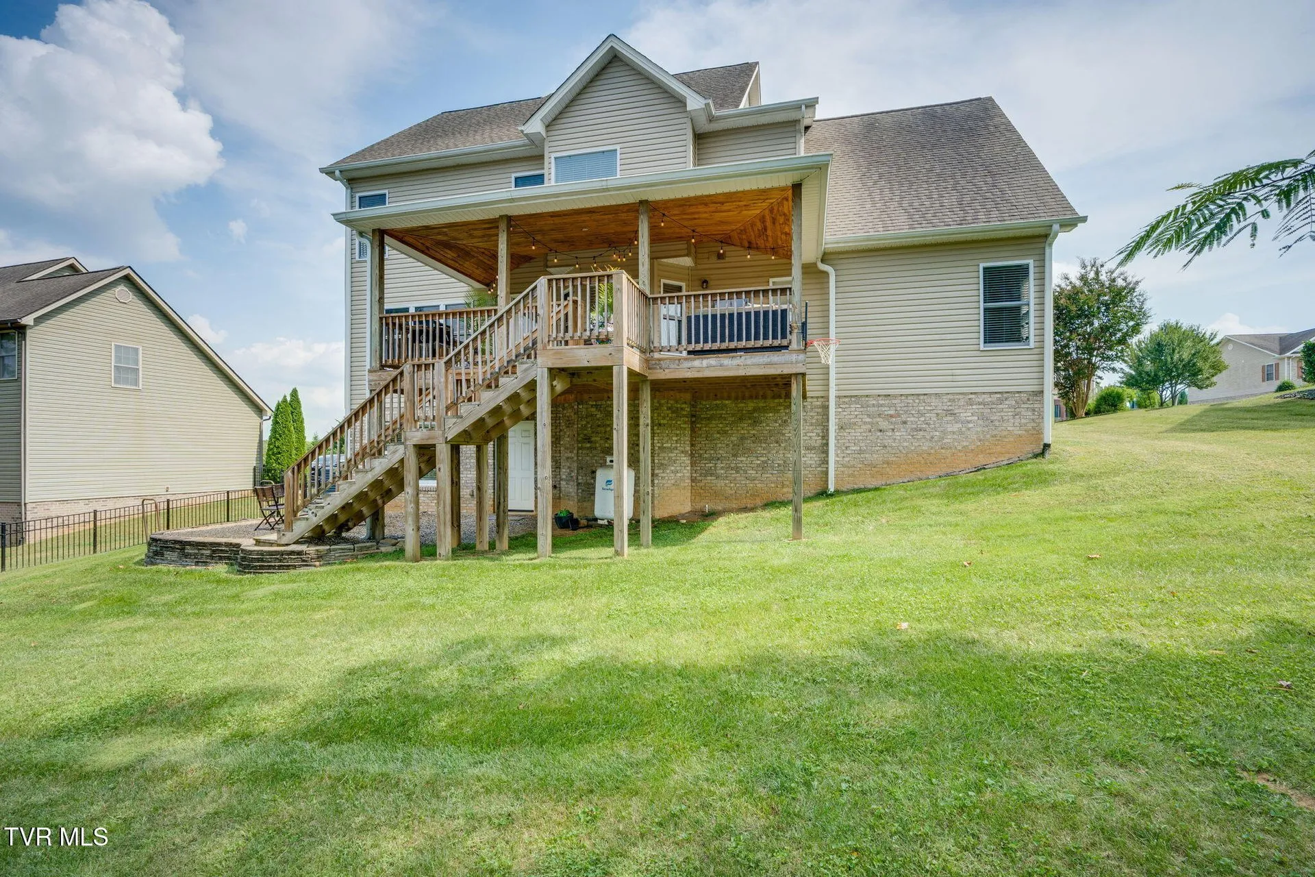 The fenced back yard with the deck stairs and the lawn