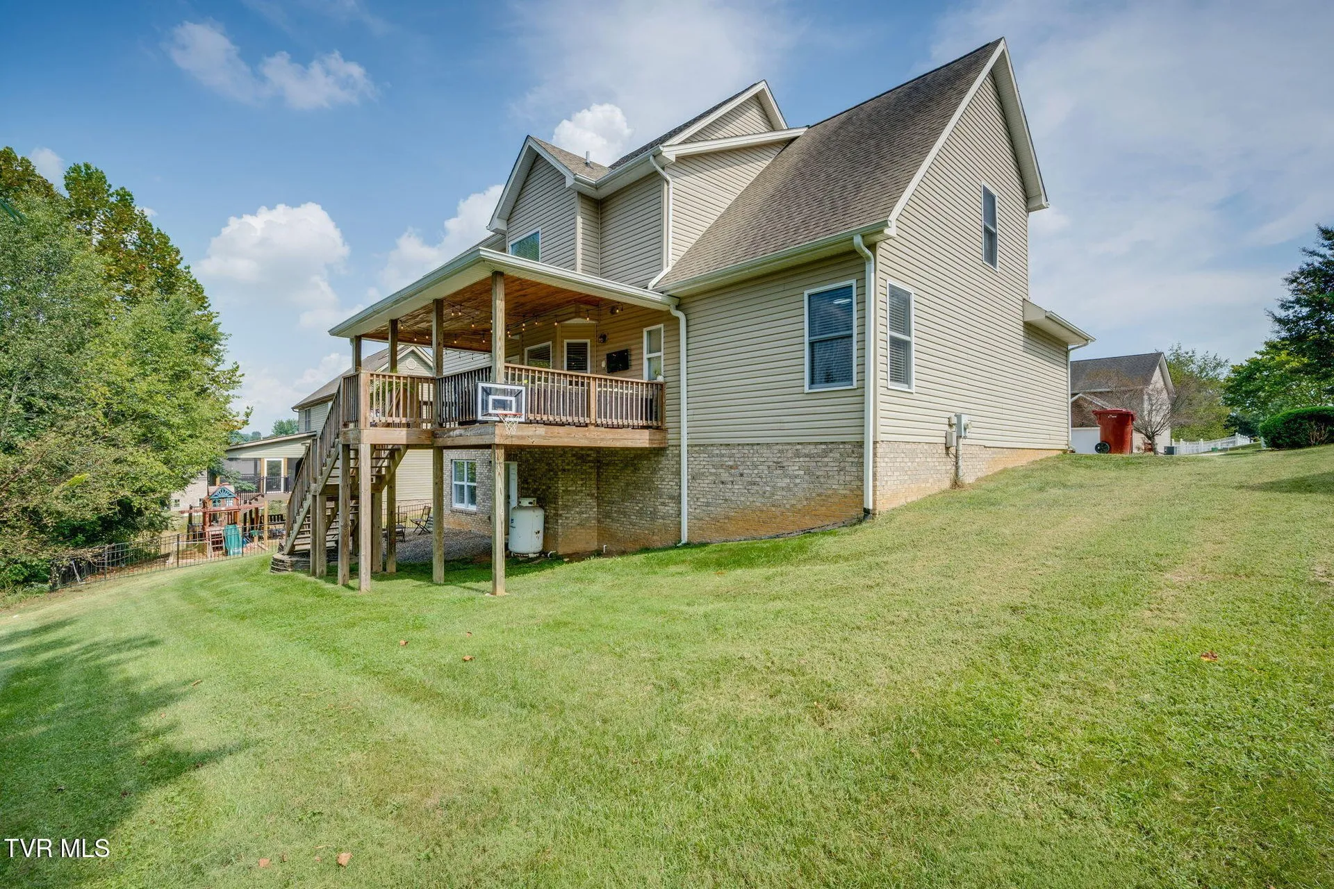 The back of the house from across the lawn with the deck and basement entry