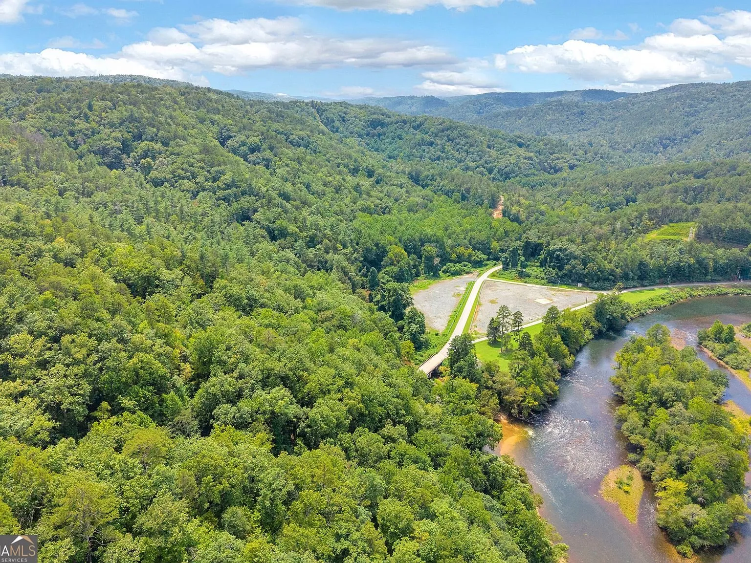 A wider view of the river bend with forested hills in the background
