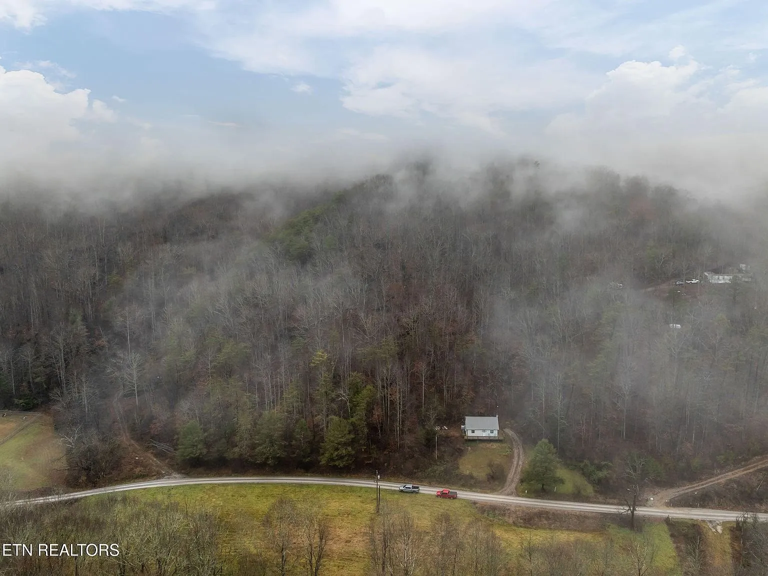 Aerial view of the property's wooded ridge under misty mountain skies