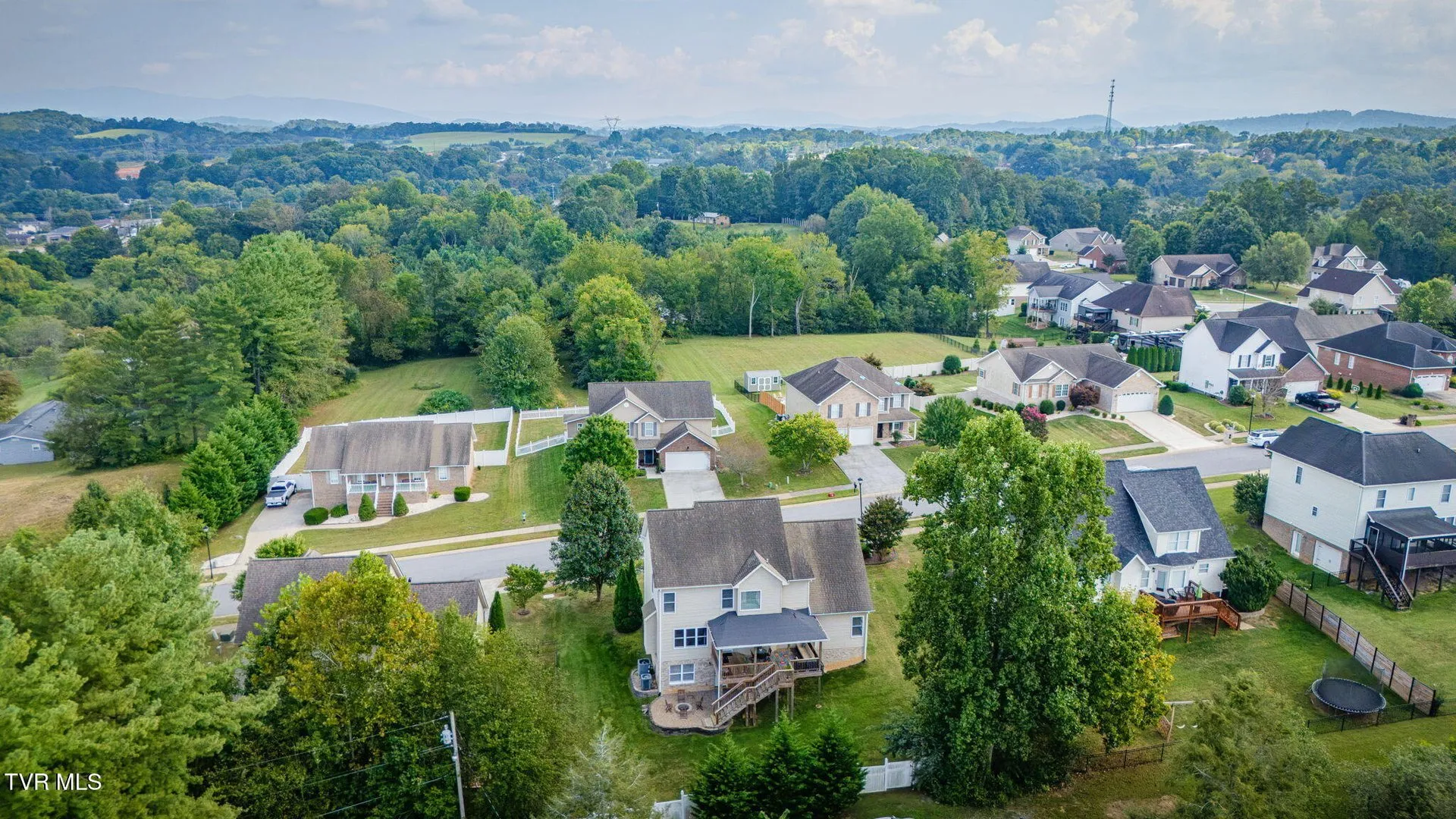 The wider view from the air with rolling country and hills beyond the subdivision
