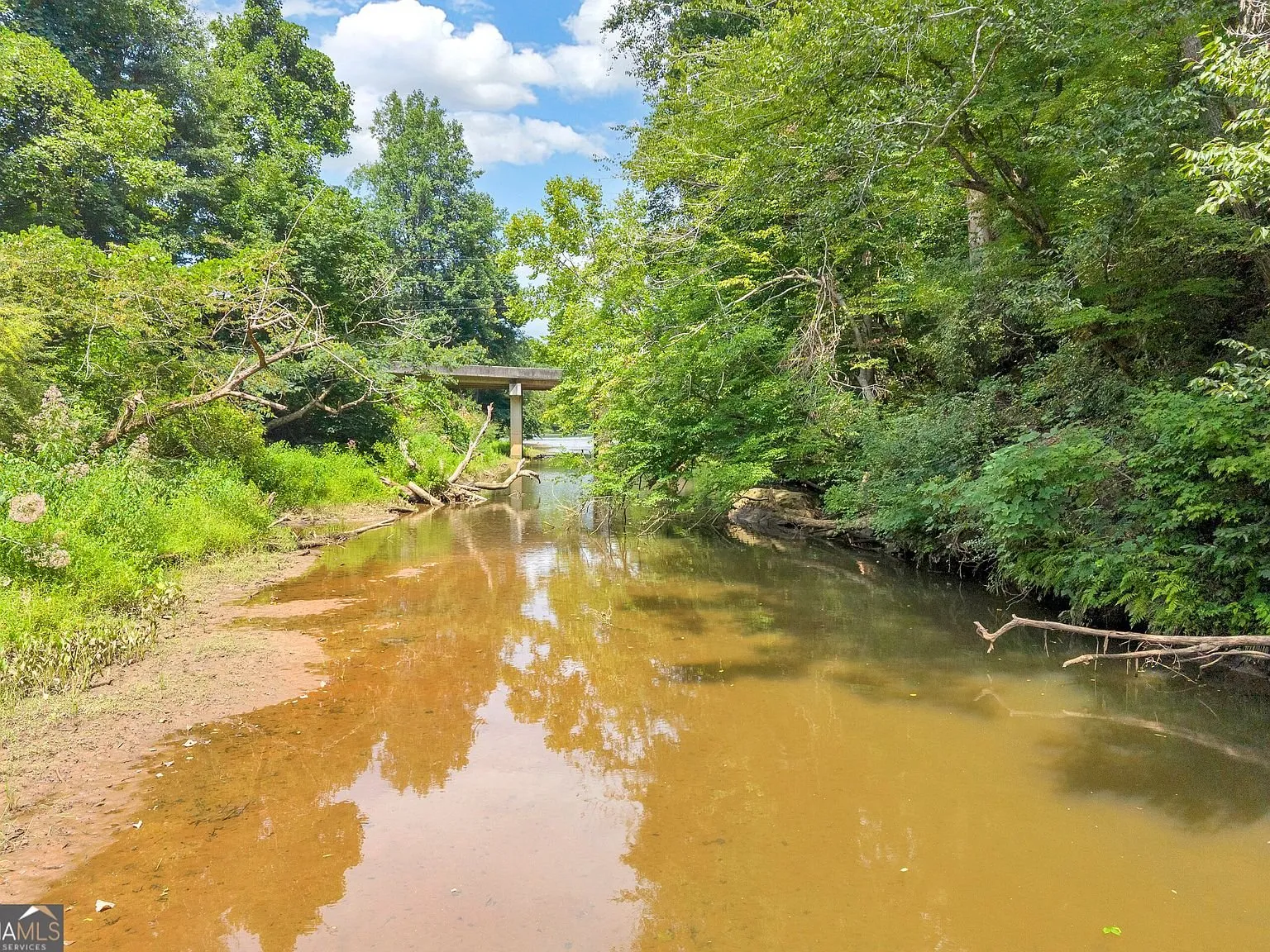 A covered outdoor seating area with a grill, adjacent to the creek