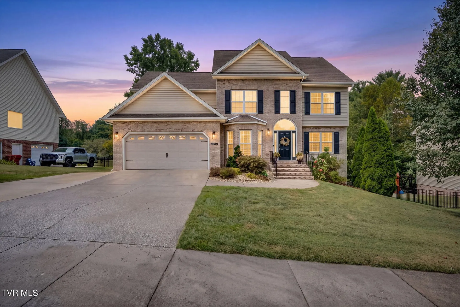 The front of the house at twilight with the windows lit and the sky in color
