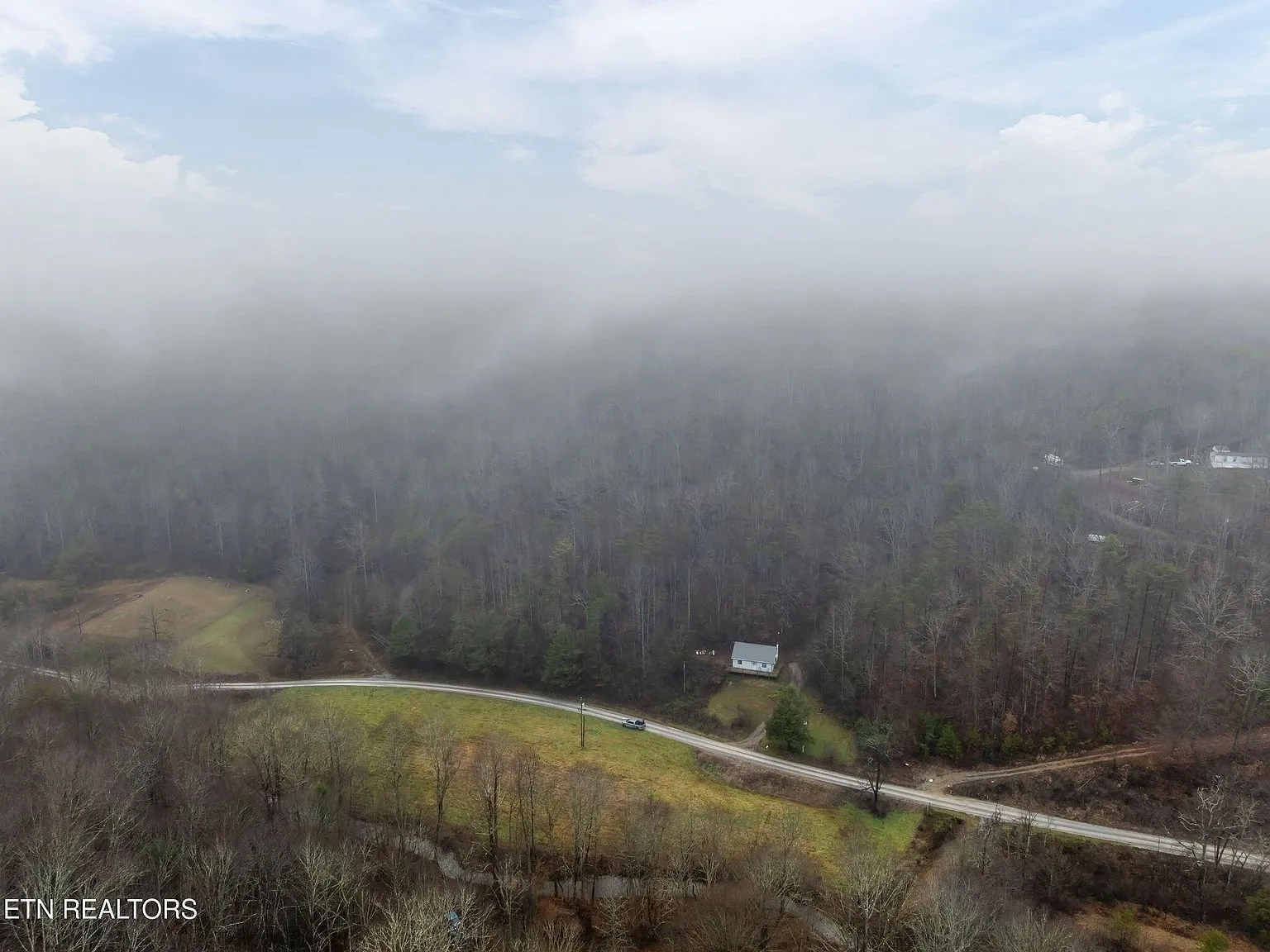 A final wide aerial view of the mountain ridge and valley fog
