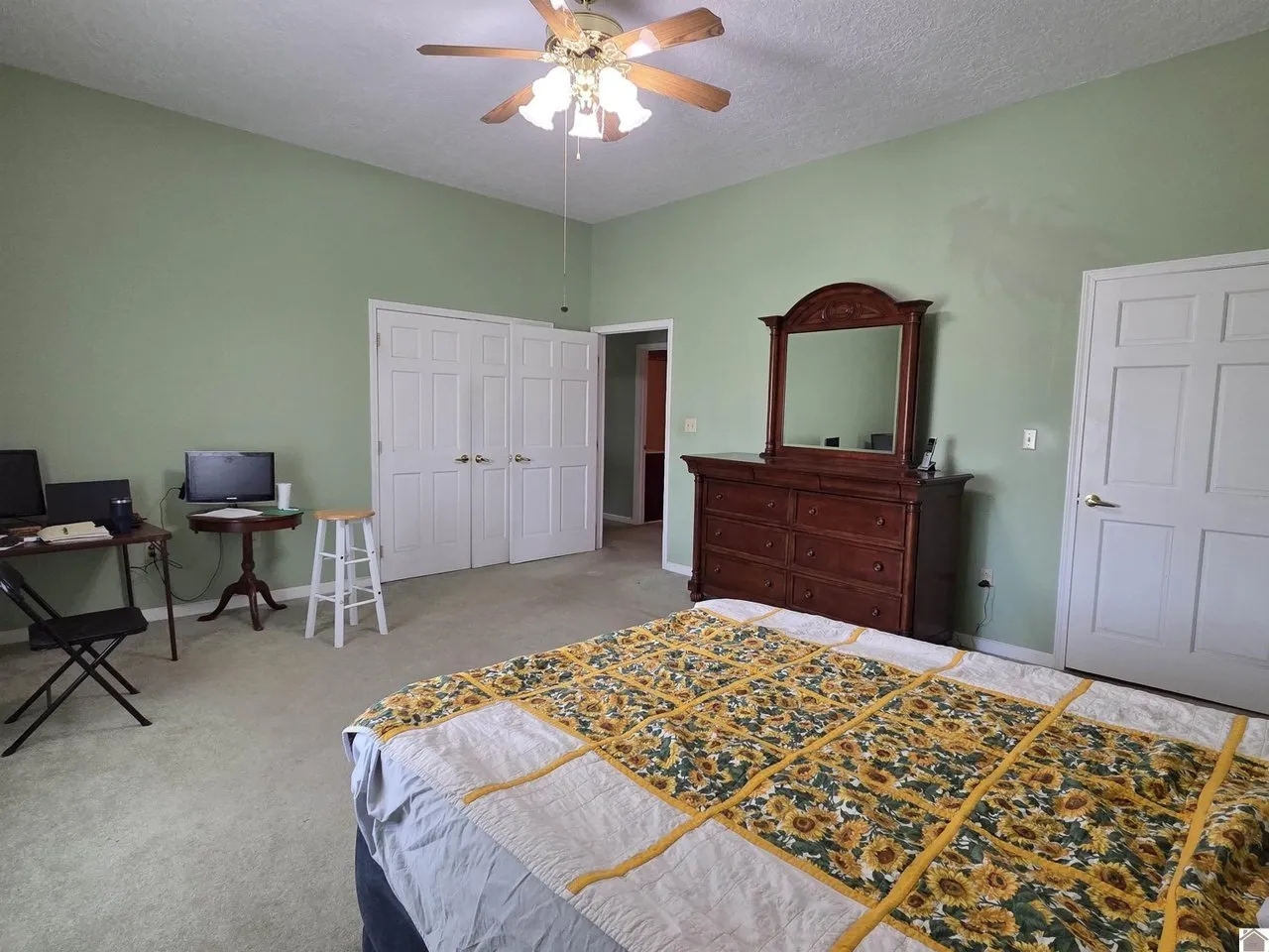 A bedroom with a ceiling fan, a dresser and closet doors
