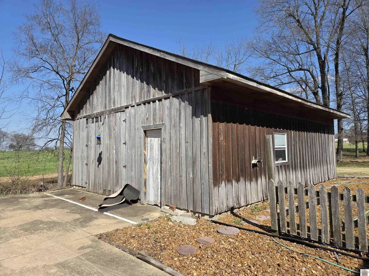The board-sided workshop building behind a picket fence