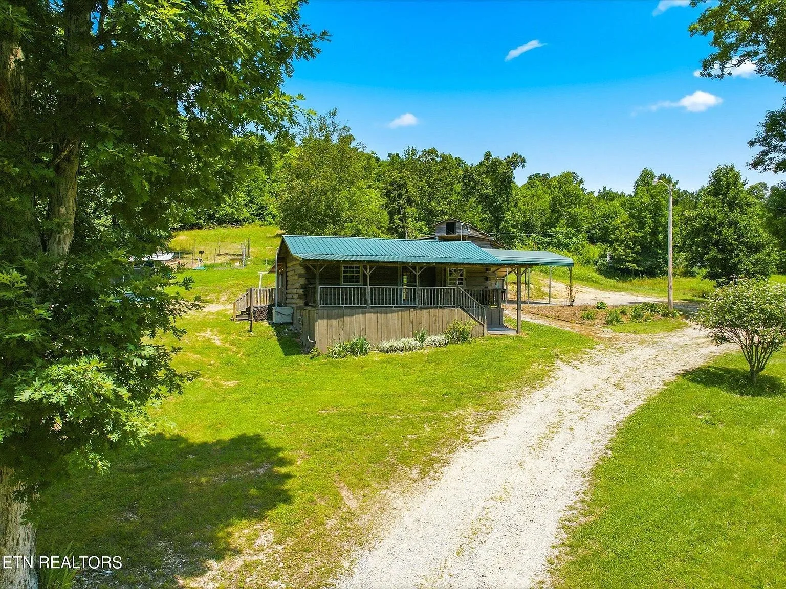 The log cabin and a carport structure seen from the driveway