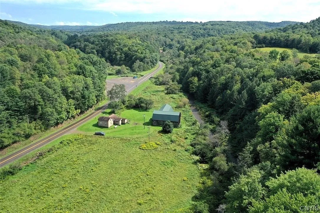 The farmhouse and the barn beside the road from the air with the valley behind