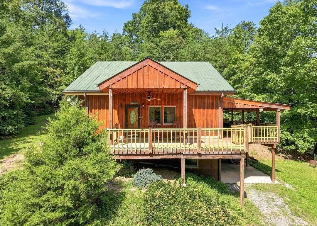 The wood-sided cabin on stilts, large covered deck visible beneath the main level