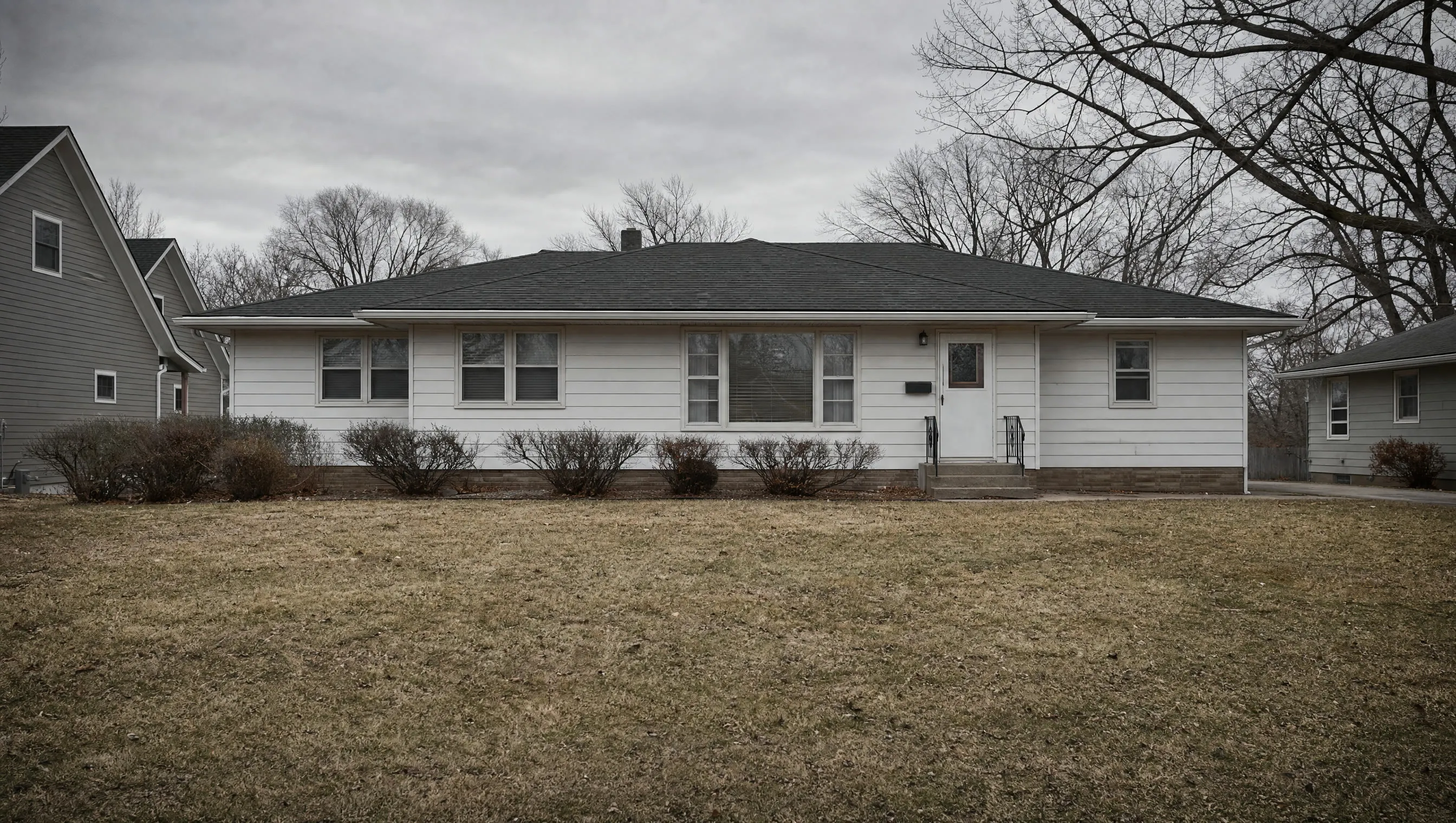 An ordinary house with an empty front yard on an overcast day