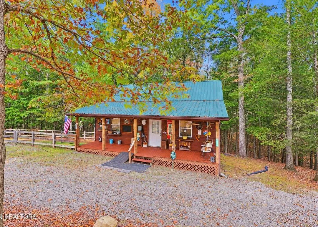 The hemlock-sided cabin seen through fall foliage, with an American flag by the porch