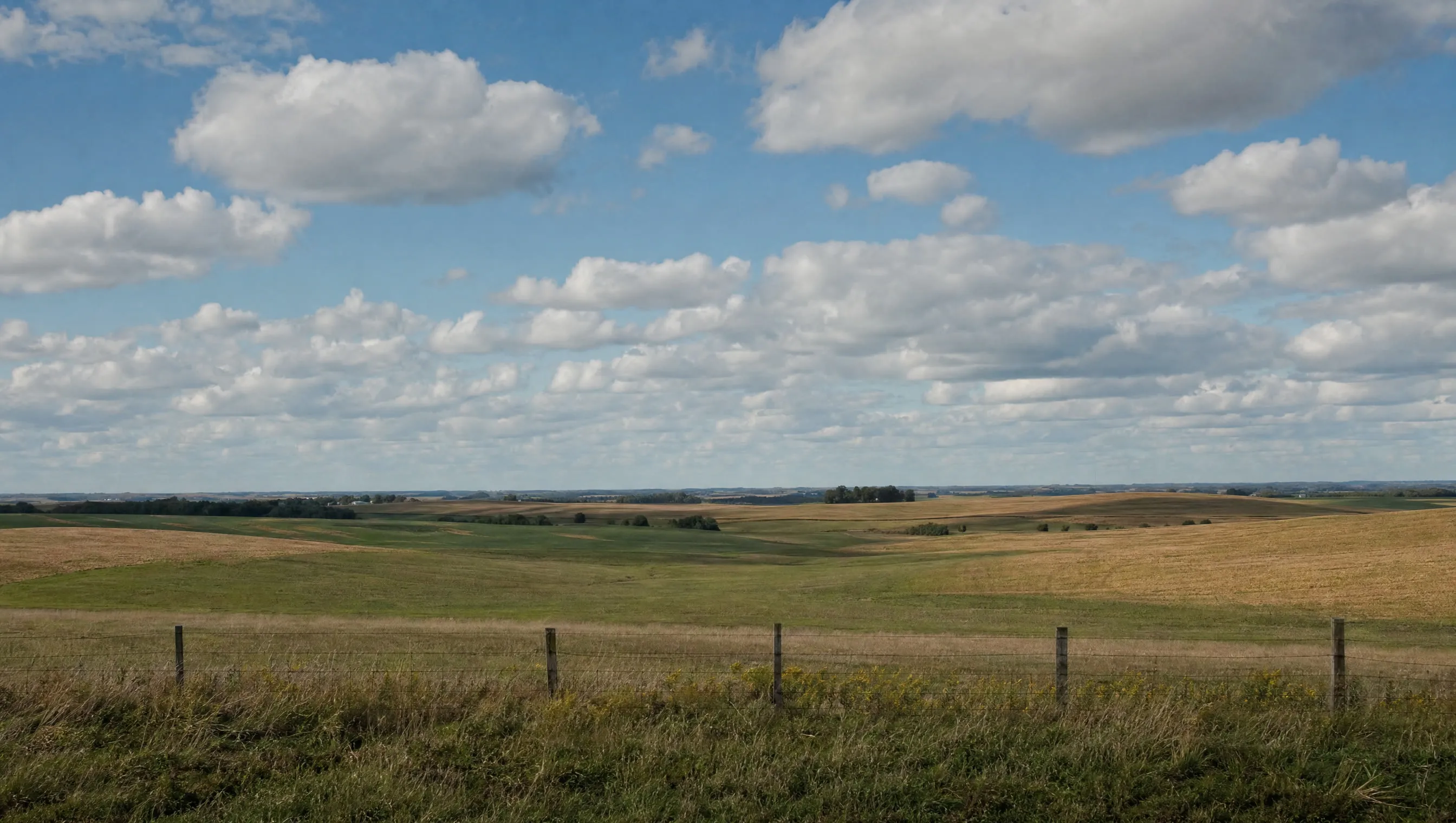 Rolling Midwestern farmland under a wide afternoon sky