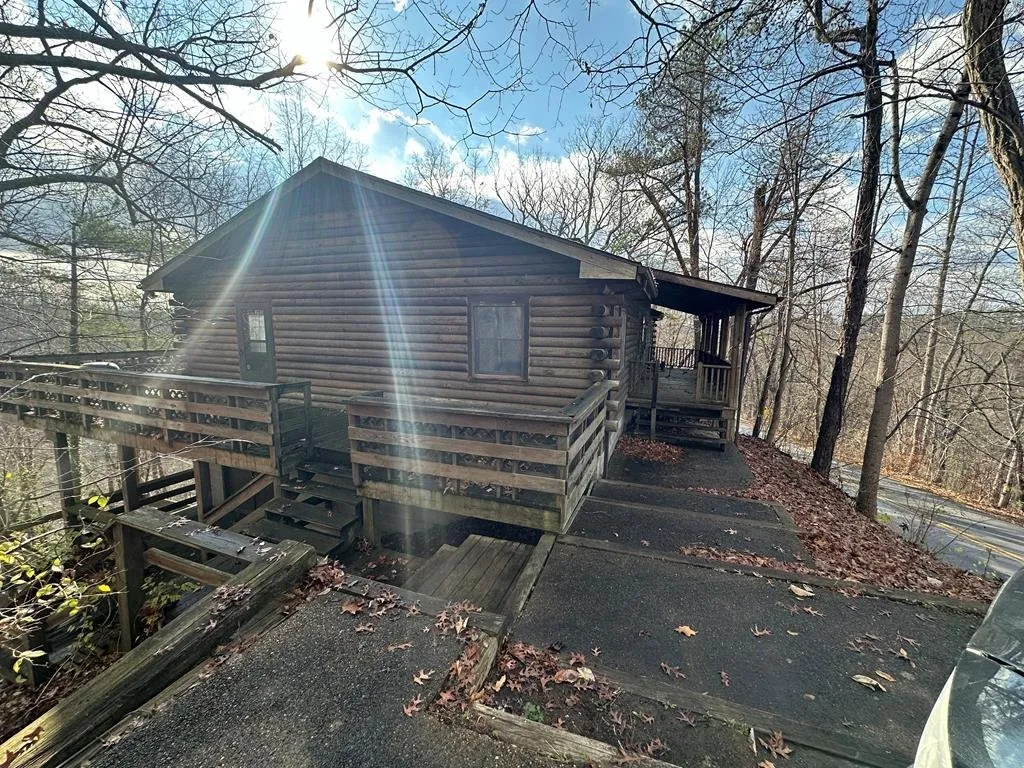 The log house on its ridge, the deck wrapping the corner and the treeline behind
