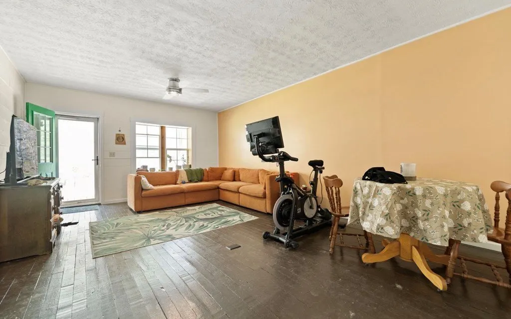 The living room with a sofa, an exercise bike and wood floors