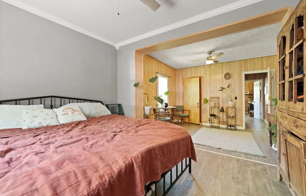 A bedroom with a red quilt and wood-paneled walls