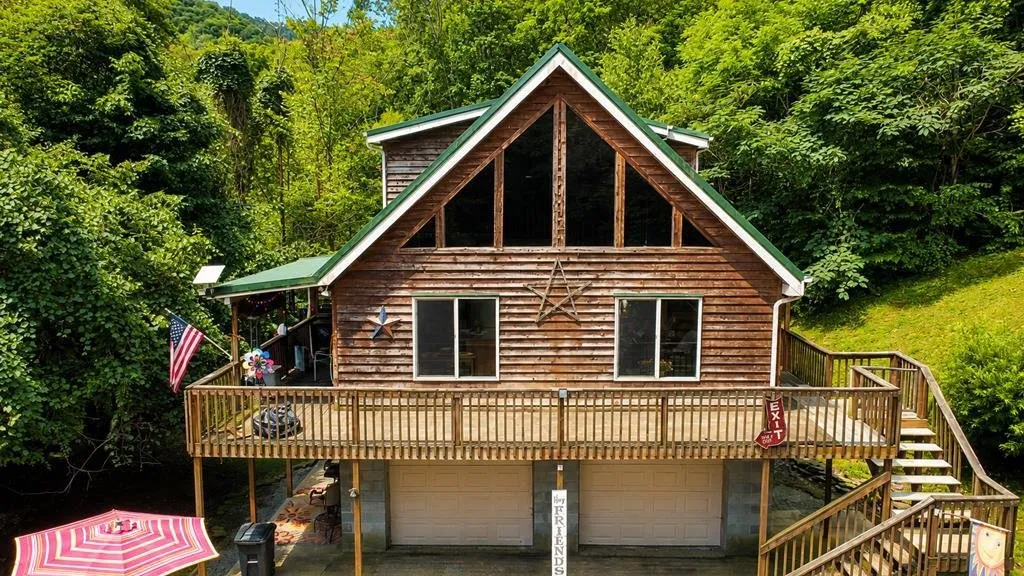 The A-frame with its green metal roof, a wraparound deck and the garage underneath