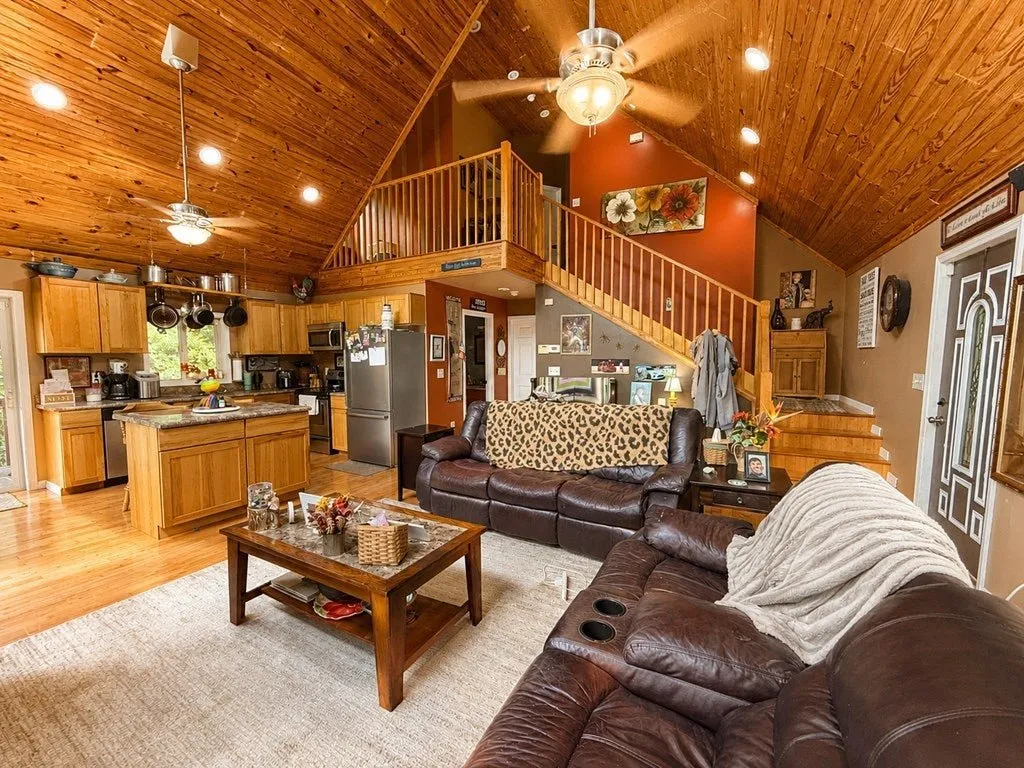 The great room under the A-frame glass, the loft railing above the kitchen