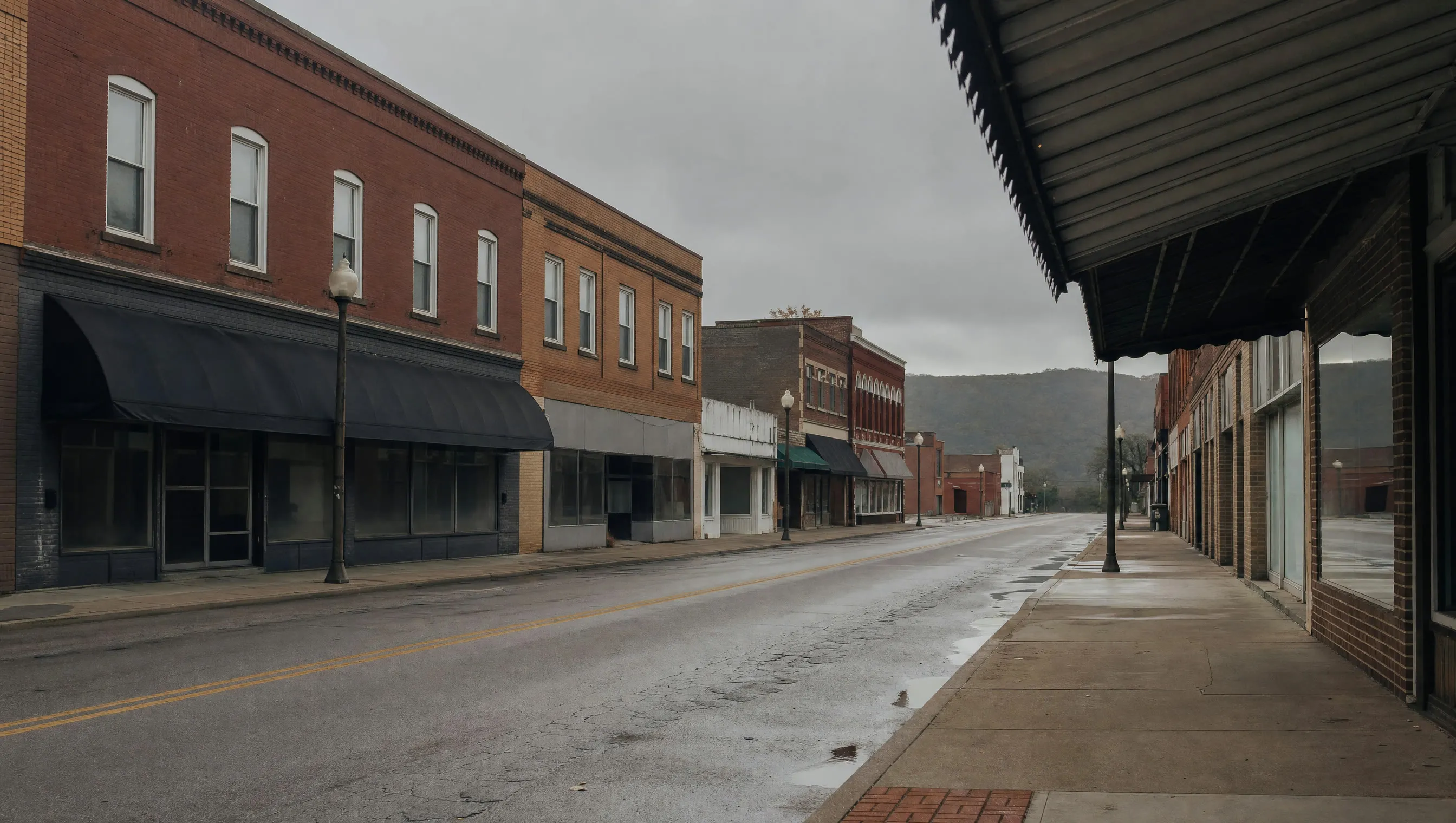 An empty small-town main street of low brick buildings on an overcast morning