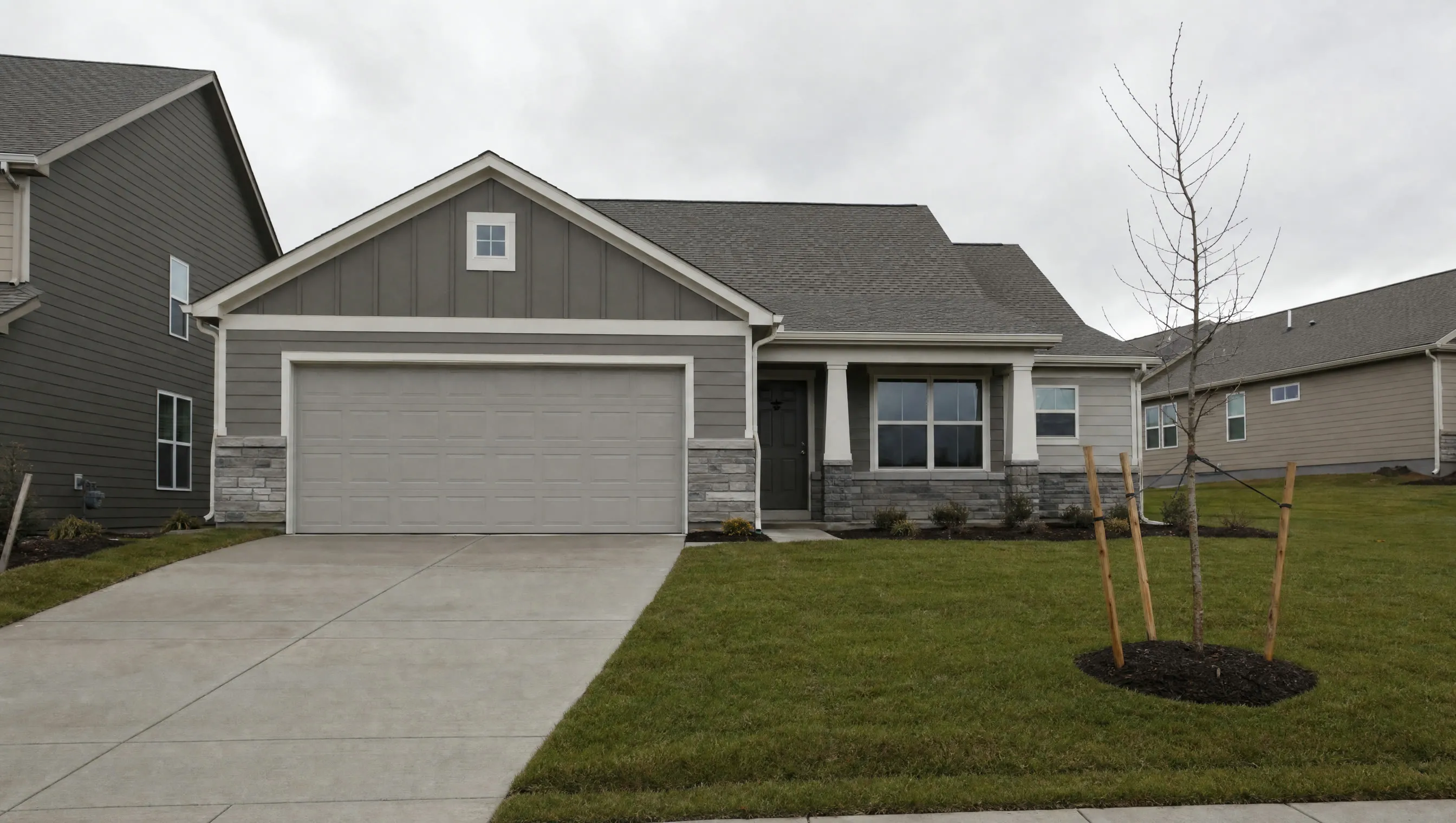 An empty concrete driveway in front of a new model home in a fresh subdivision