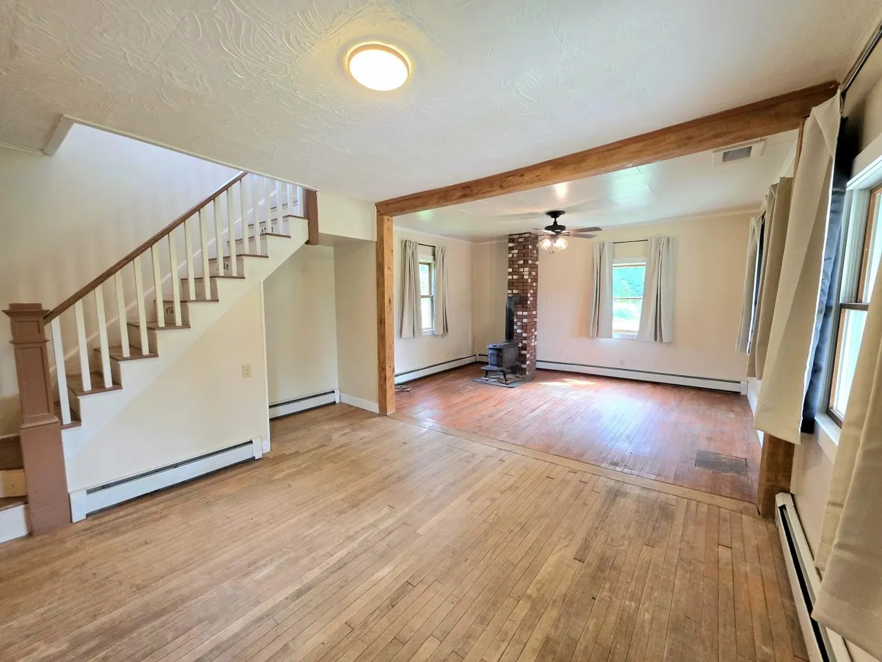 The living room with wood floors, a beam and the stairs to the second floor