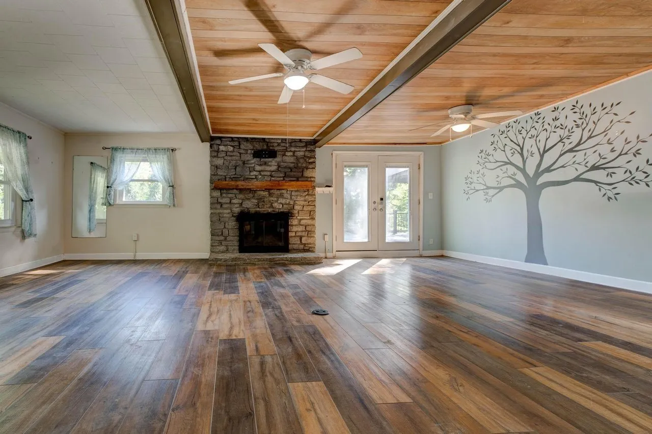 The main room with a stone fireplace, wide plank floors and a wood-clad ceiling